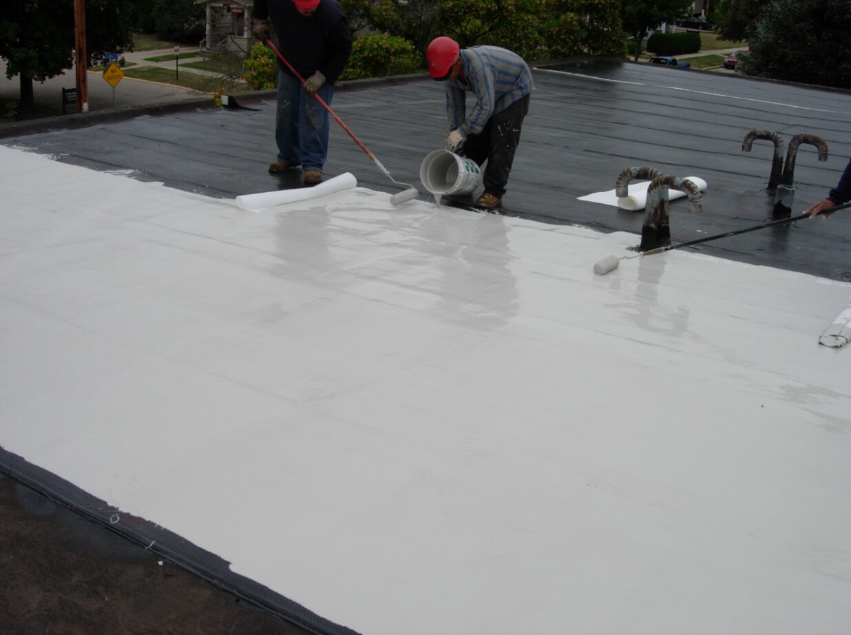 Two Siplast PMMA seasoned contractors pouring and rolling pmma roof membrane on a roof